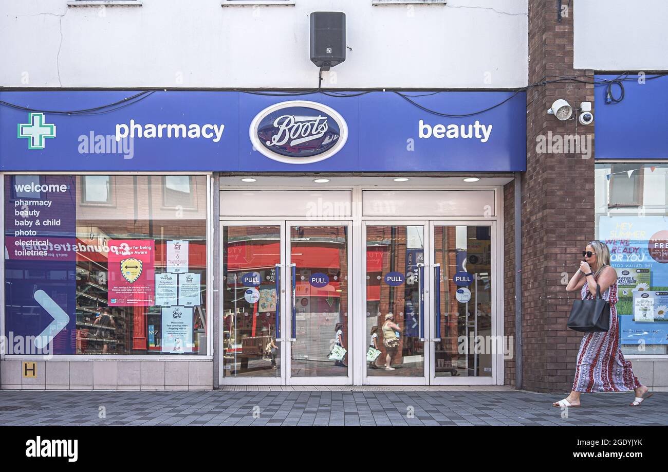 Lisburn, Regno Unito. 18 luglio 2021. Una donna al telefono cammina oltre Boots Farmacia e negozio di bellezza su Bow Street a Lisburn. Credit: SOPA Images Limited/Alamy Live News Foto Stock