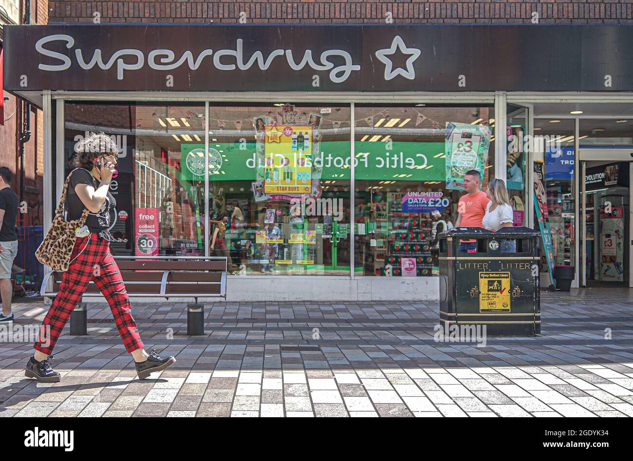 Belfast, Regno Unito. 18 luglio 2021. Una donna al telefono passa davanti alla Superdrug Pharmacy e al Beauty Store in Ann Street a Belfast. Credit: SOPA Images Limited/Alamy Live News Foto Stock
