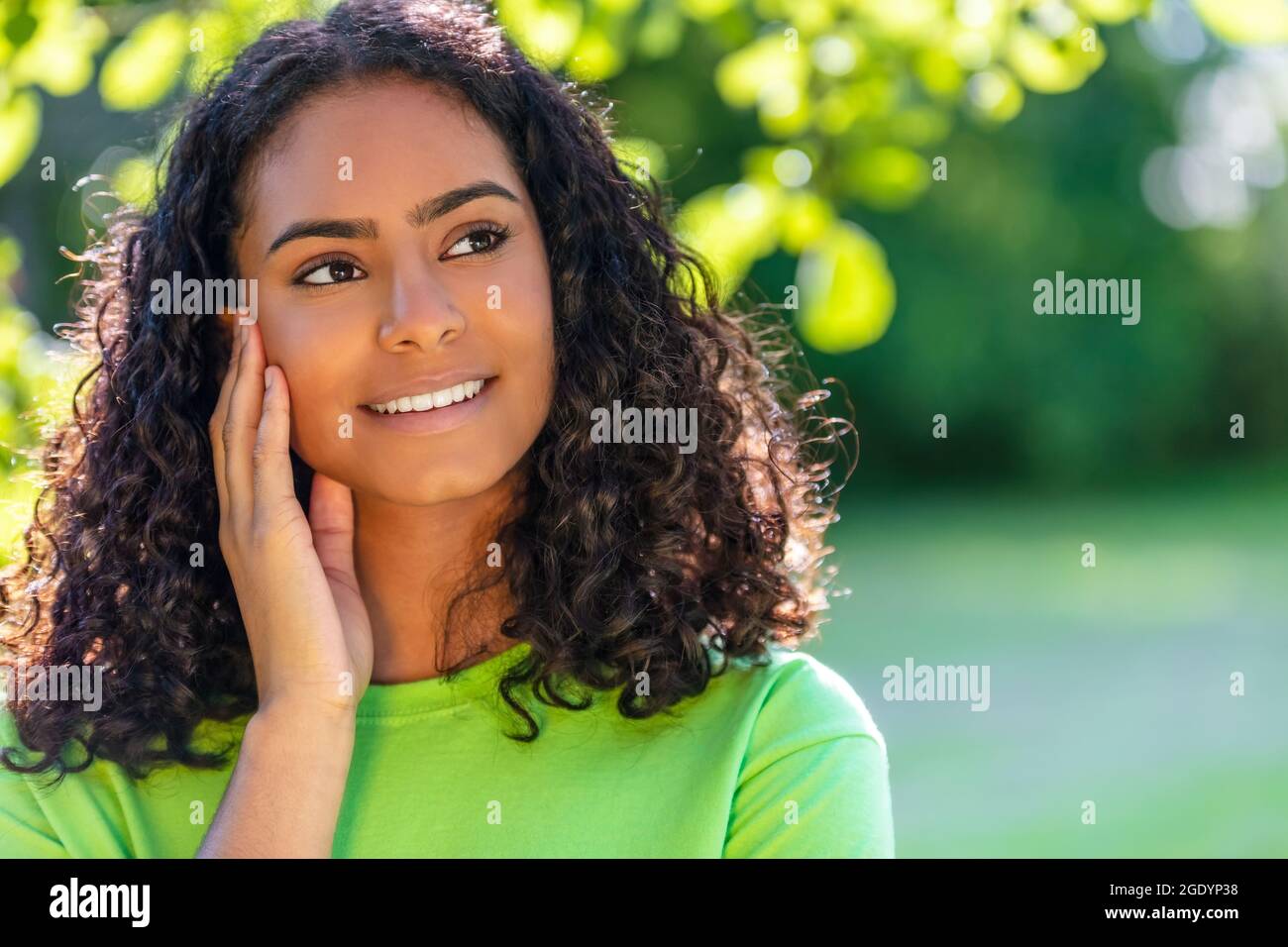 Ritratto esterno di bella corsa mista felice Africana americana ragazza adolescente femmina giovane donna che pensa e sorridendo con denti perfetti con una natura Foto Stock