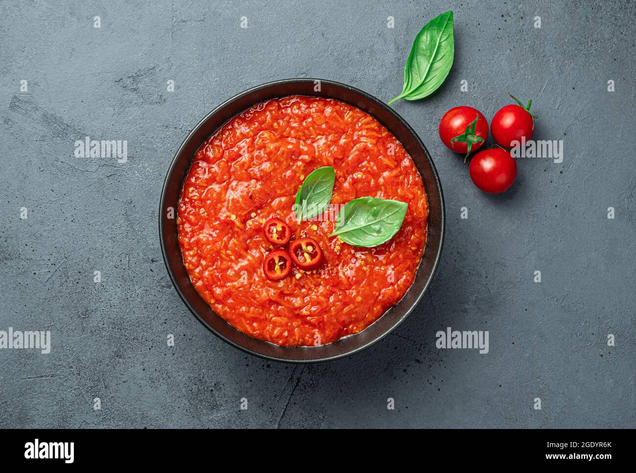 Salsa di pomodoro con pepe caldo e basilico su sfondo grigio-blu. Foto Stock