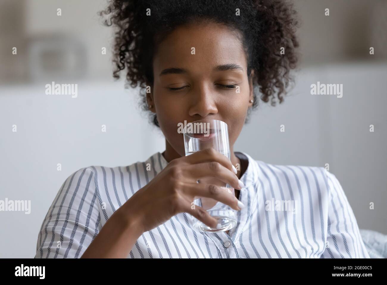 Donna etnica assetata bere acqua pulita dal vetro Foto Stock