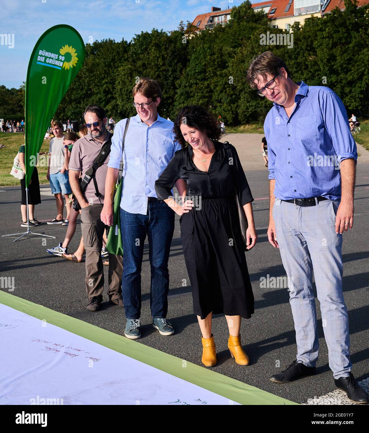 Berlino, Germania. 15 agosto 2021. Jochen Biedermann (2° da sinistra a destra, Bündnis 90/ Die Grünen), consigliere distrettuale di Neukölln, Bettina Jarrasch (Bündnis 90/ Die Grünen), candidato sindaco di Berlino, e Michael Kellner, responsabile della campagna del Partito Verde e direttore nazionale, stanno di fronte a un grande banner su Tempelhofer Feld. Per dare il via alla campagna elettorale postale, i cittadini potrebbero scrivere i loro desideri di un governo verde su questo banner sul campo. Credit: Annette Riedl/dpa/Alamy Live News Foto Stock