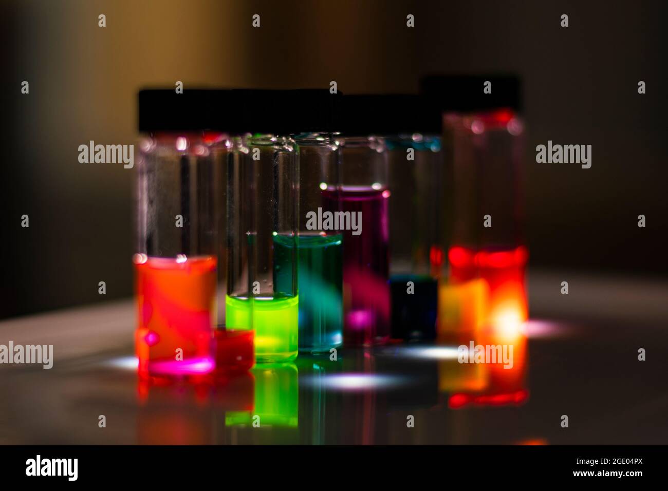 Vari reagenti colorati in fiale di vetro su luce UV in un laboratorio di biotecnologia per esperimenti farmaceutici per lo sviluppo di farmaci Foto Stock