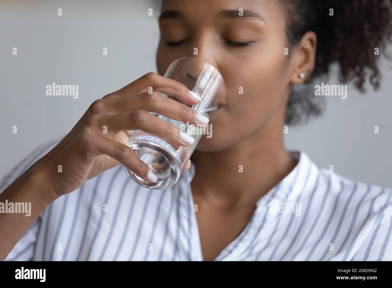 Primo piano di assetata biracial donna bere acqua Foto Stock