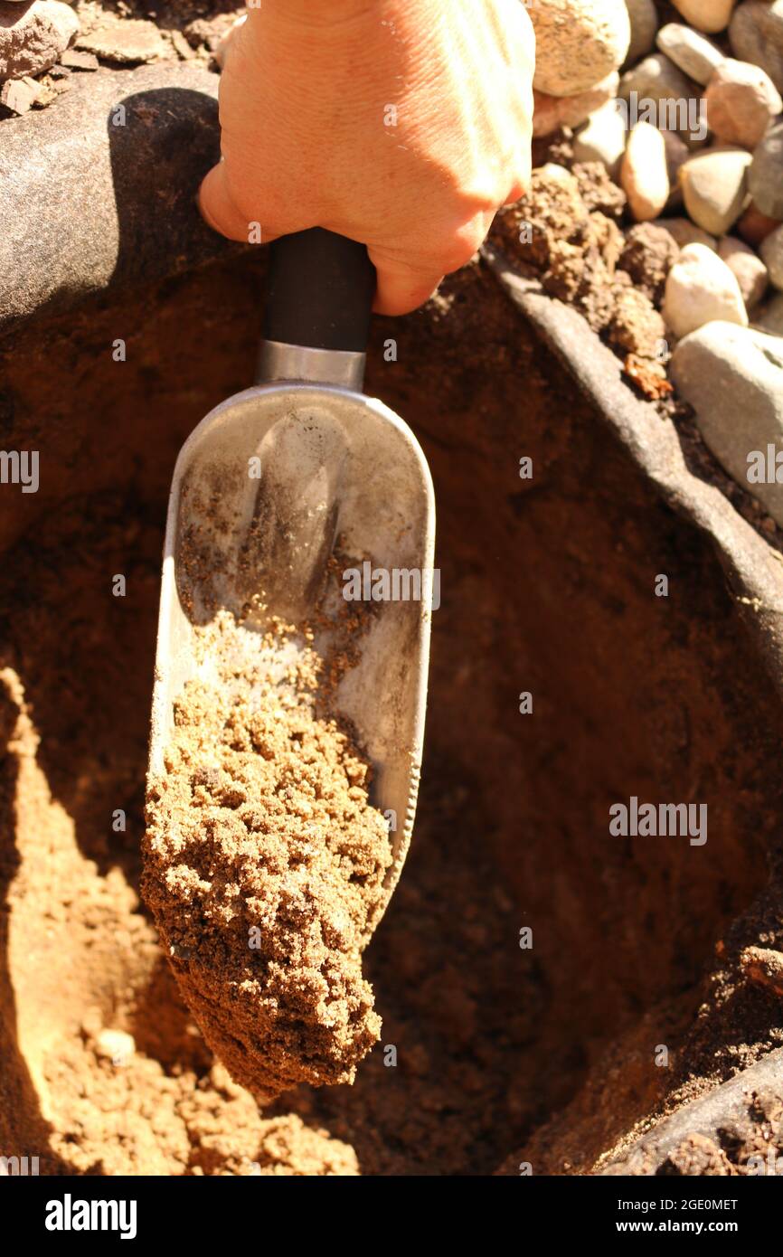 Utilizzando una cazzuola da giardino per scavare un buco. Foto Stock