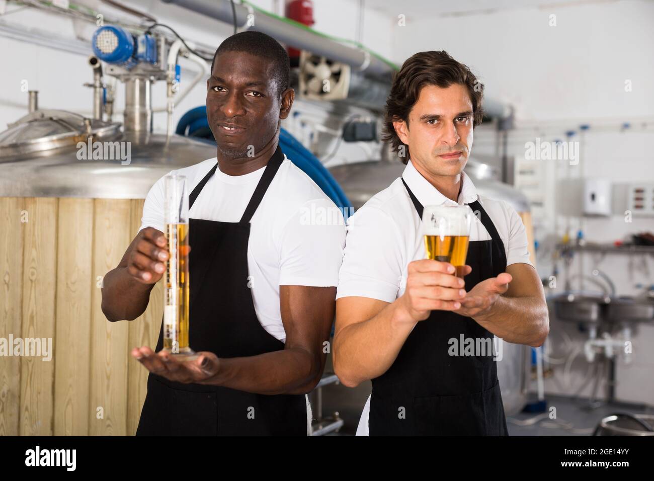 Due produttori di birra professionisti che mostrano il bicchiere e la bottiglia di birra Foto Stock