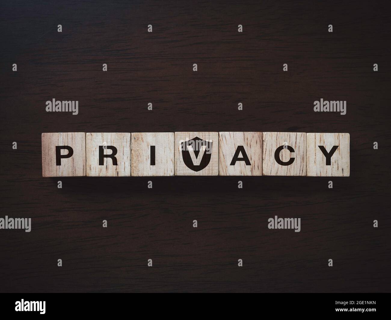 Concetto di privacy. Parola 'PRIVACY' su blocchi di legno con un'icona di scudo su sfondo di legno scuro, vista dall'alto. Protezione dei dati personali e non violazione Foto Stock