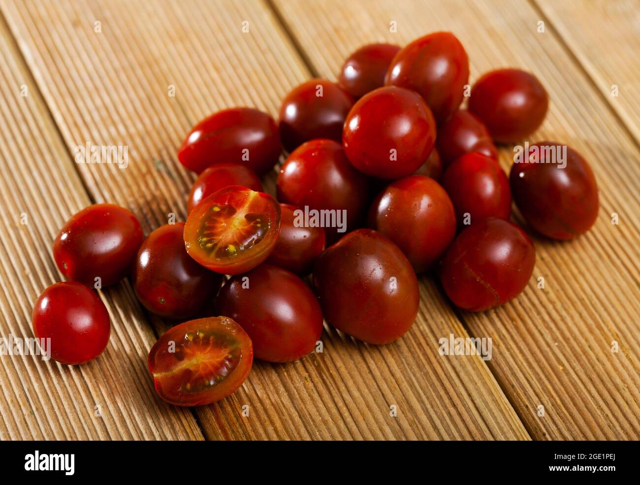 Pomodori kumato di specie coltivate a rosso maturo su fondo ligneo. Foto Stock