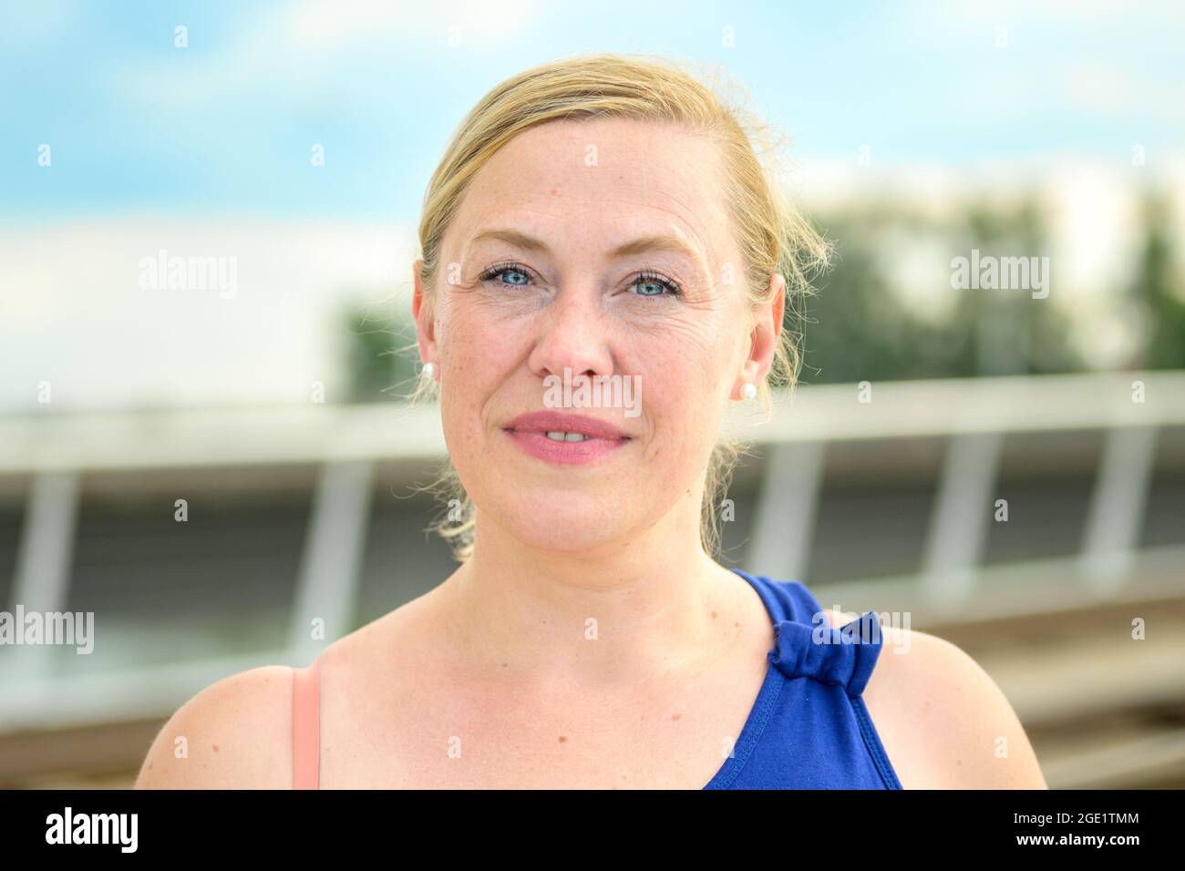Primo piano di una donna di mezza età che guarda la fotocamera in silenzio con un sorriso penoso Foto Stock