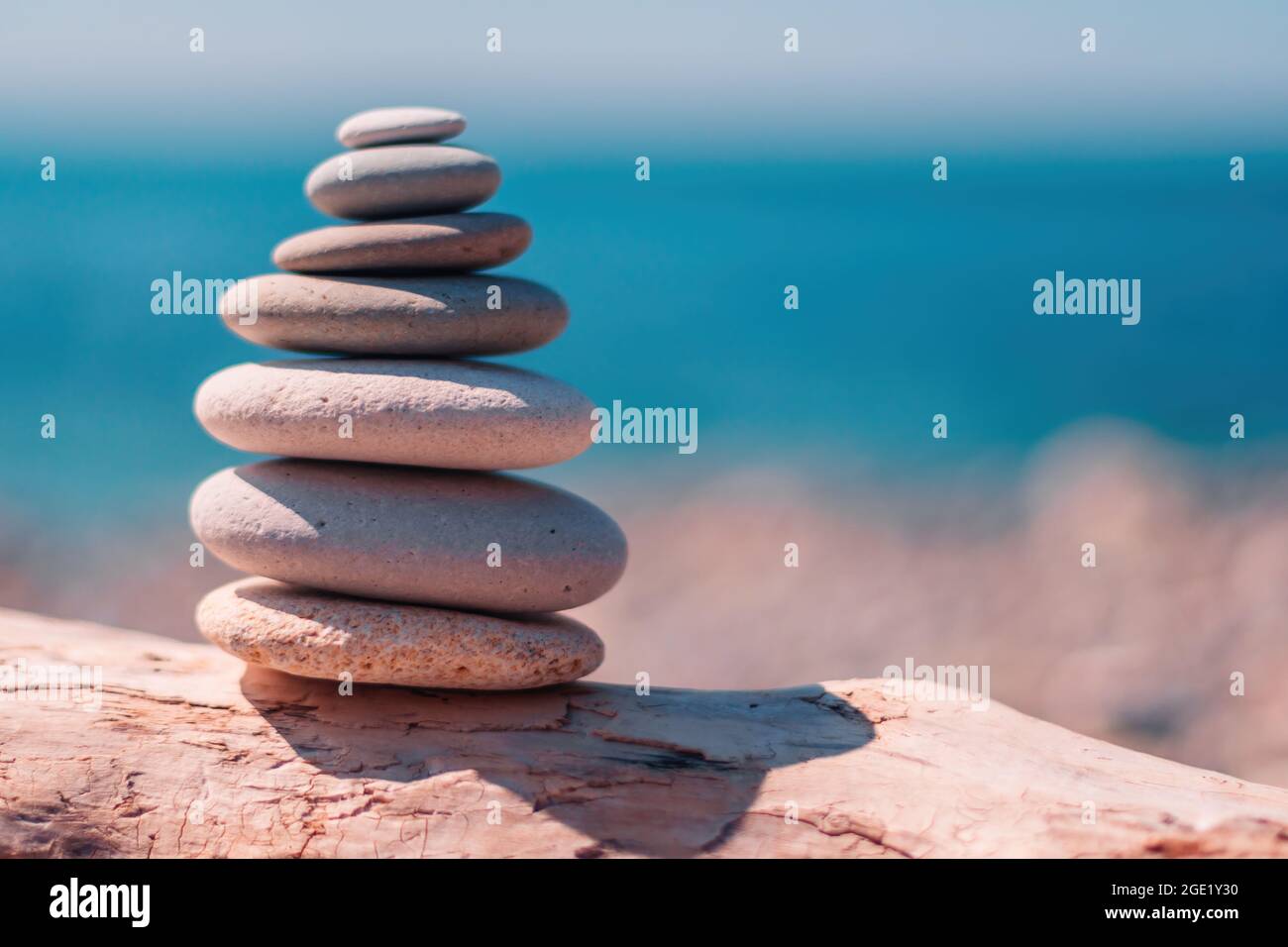 Equilibrata piramide di ciottoli sulla spiaggia in una giornata di sole. Abstract Sea bokeh sullo sfondo. Messa a fuoco selettiva. Pietre Zen sulla spiaggia di mare, meditazione Foto Stock