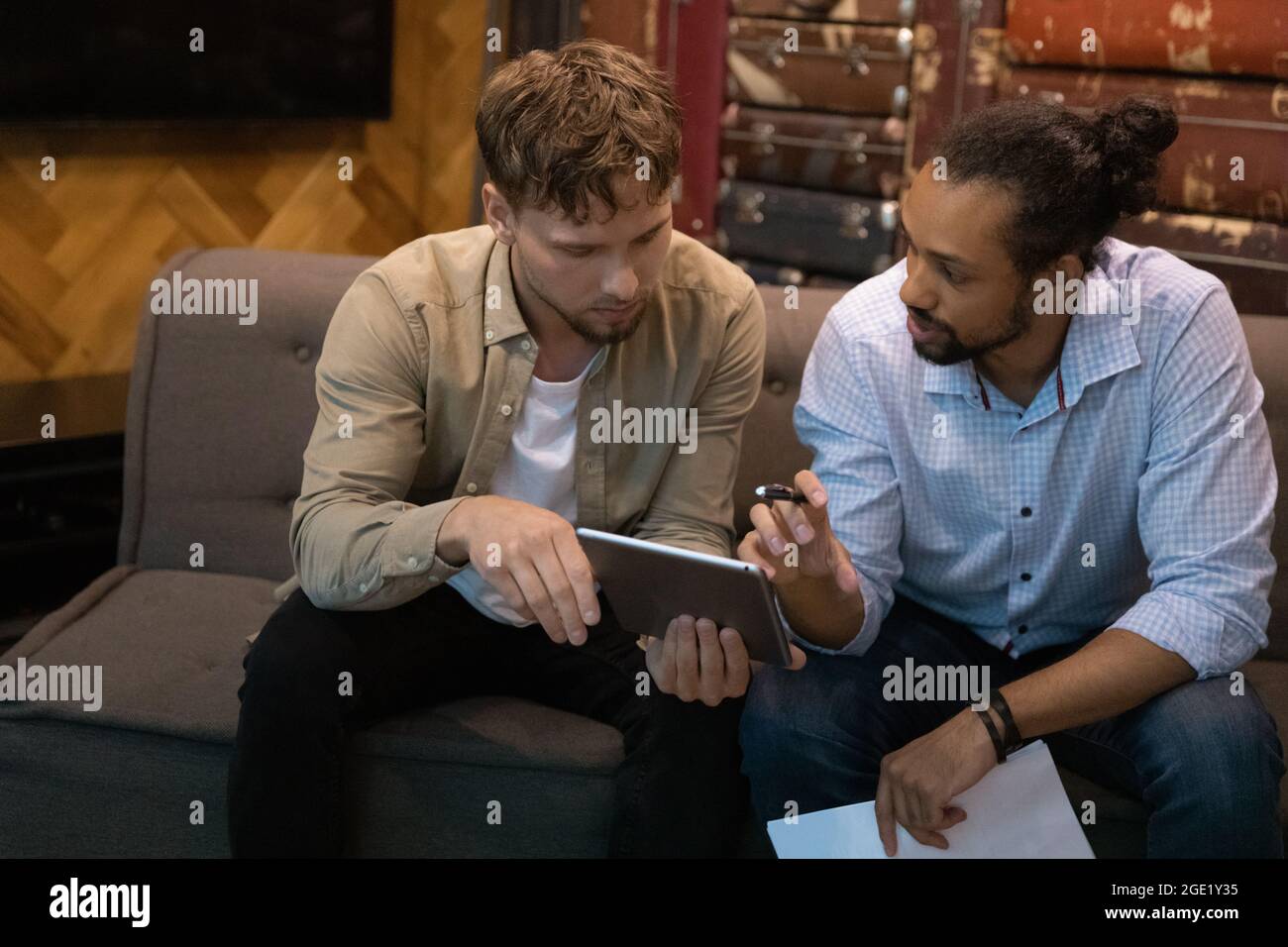 I compagni di squadra multietnici discutono di un progetto collaborativo utilizzando un tablet digitale Foto Stock