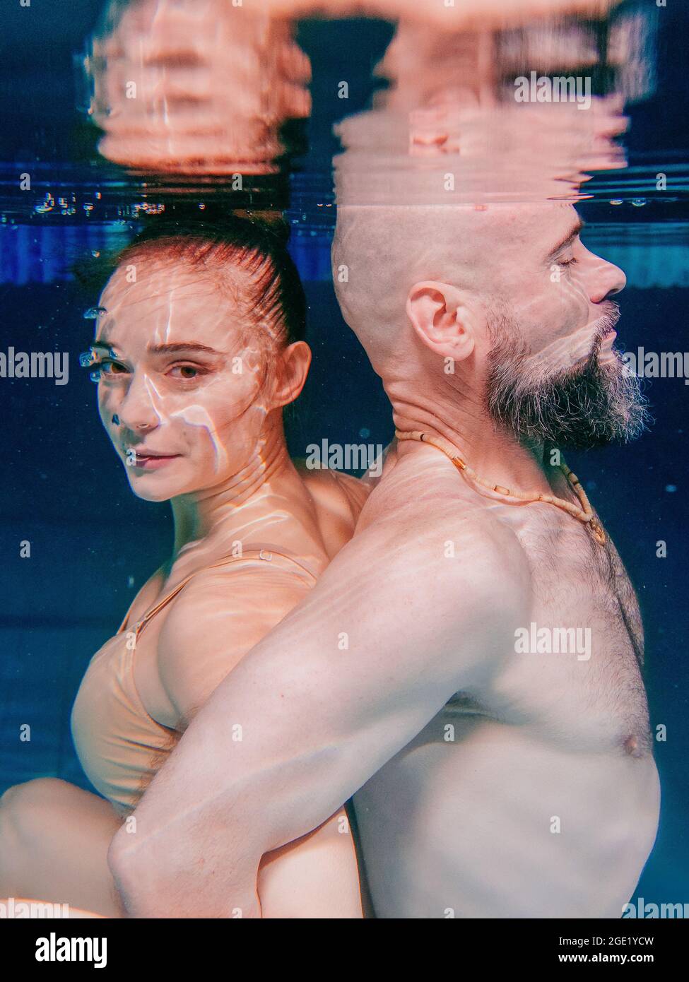 ritratto subacqueo della danza atletica, sportiva e fare yoga asana coppia (uomo e donna) sott'acqua in piscina Foto Stock