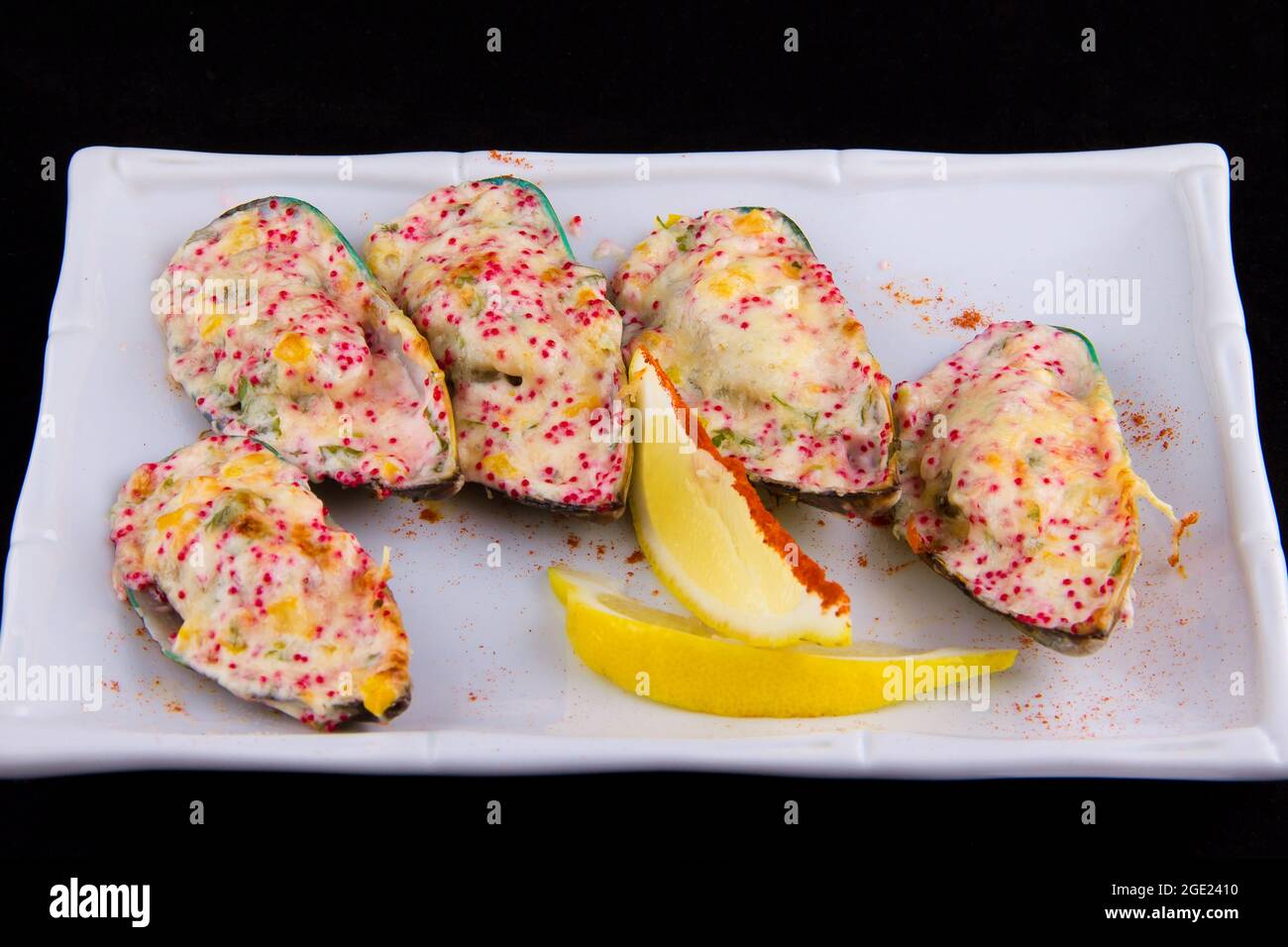 Le cozze kiwi, note anche come verdi, verdi-lipped, giganti e Nuova Zelanda, cotte al forno con salsa al formaggio, peperone, parmigiano, roe di pesce volante tobiko. Foto Stock