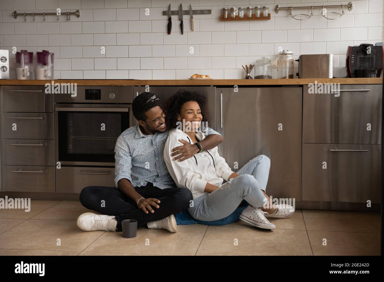 La coppia millenaria africana si siede sul pavimento in cucina Foto Stock