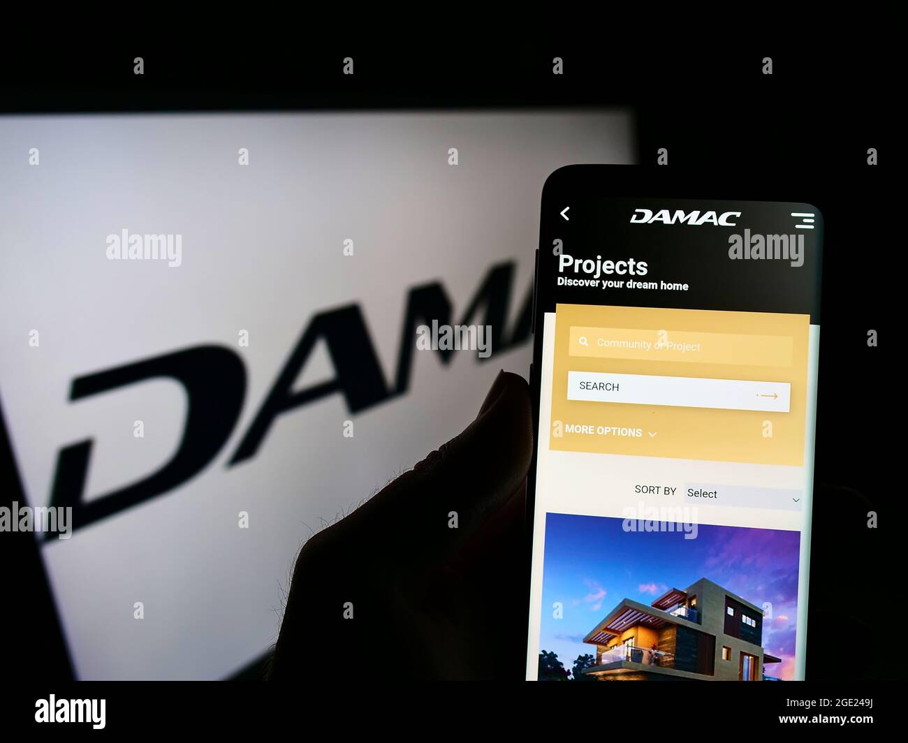 Persona titolare cellulare con pagina web della società immobiliare Emirati DAMAC Proprietà su schermo davanti al logo. Mettere a fuoco il centro del display del telefono. Foto Stock
