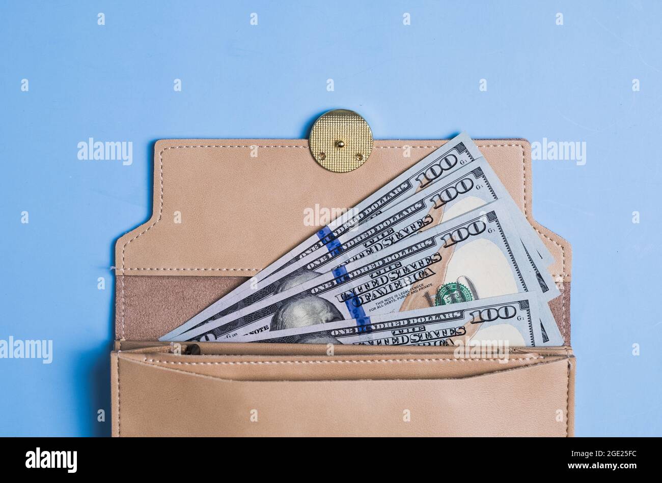 Banconote da 100 dollari con e portafoglio su sfondo blu. Foto Stock