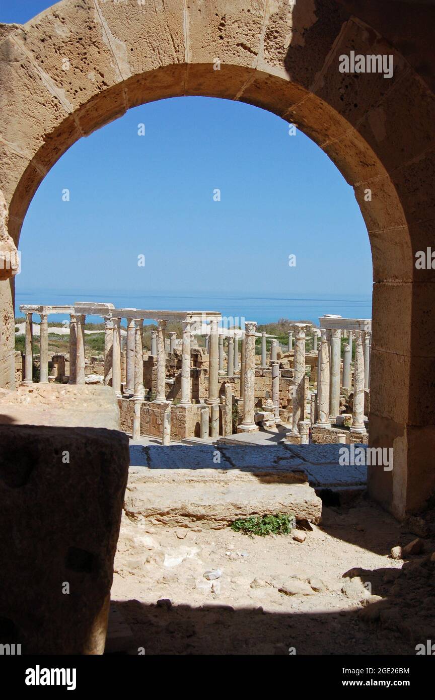 Vista attraverso un arco in cima alla fila di posti a sedere presso l'antico anfiteatro romano a Leptis Magna, Libia. Foto Stock