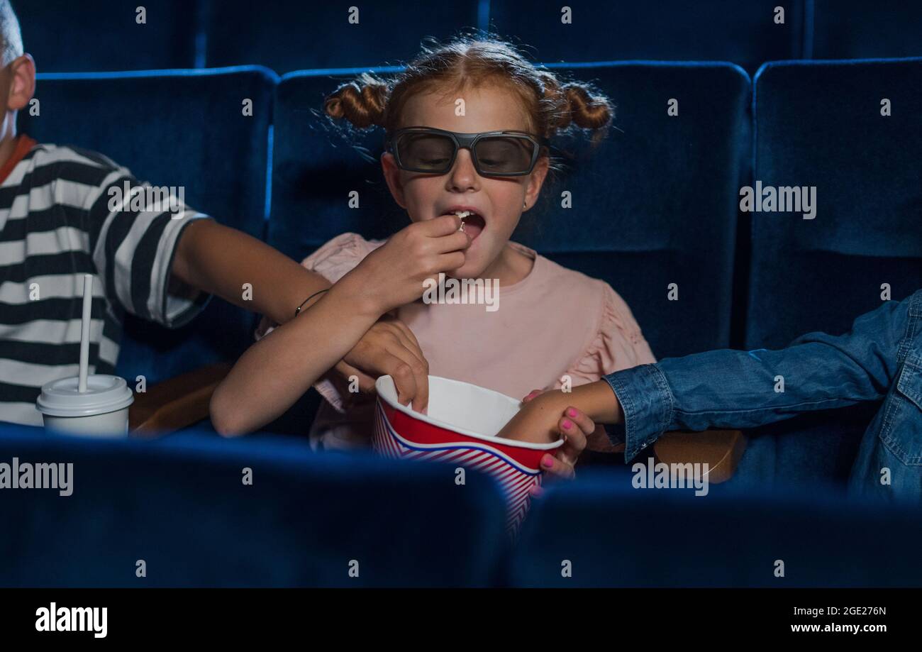 Felici i bambini con occhiali 3d al cinema, guardando film e mangiando popcorn. Foto Stock