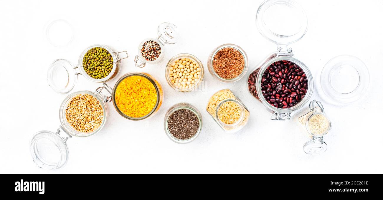 Drogheria, scorte domestiche in plastica di deposito libero e vasi. Fagioli vari, grani, cereali, legumi, semi in lattine riutilizzabili. Tavola bianca. Zero rifiuti e su Foto Stock
