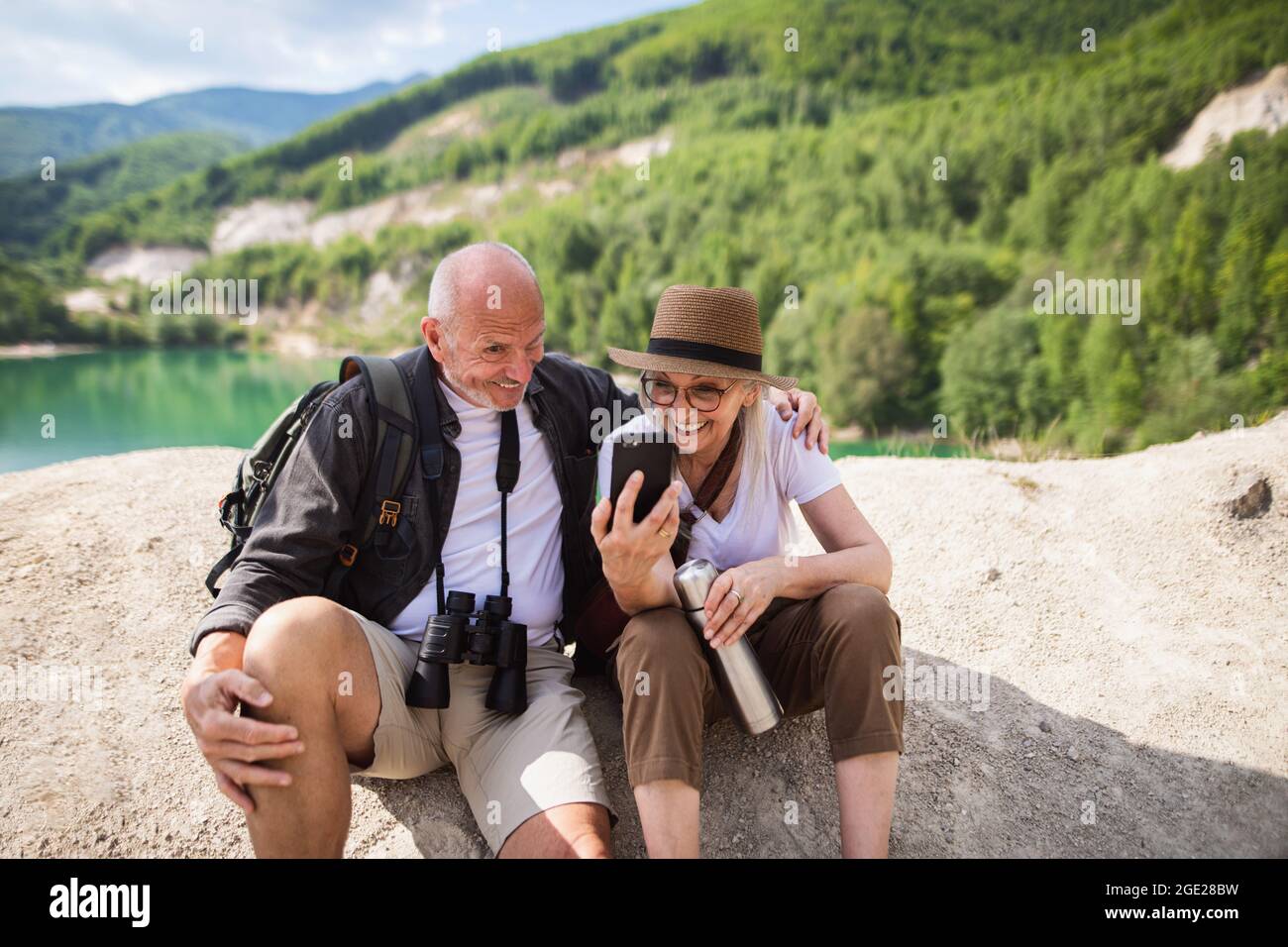 Felice coppia senior in viaggio escursionistico in vacanza estiva, facendo volti quando si prende selfie. Foto Stock