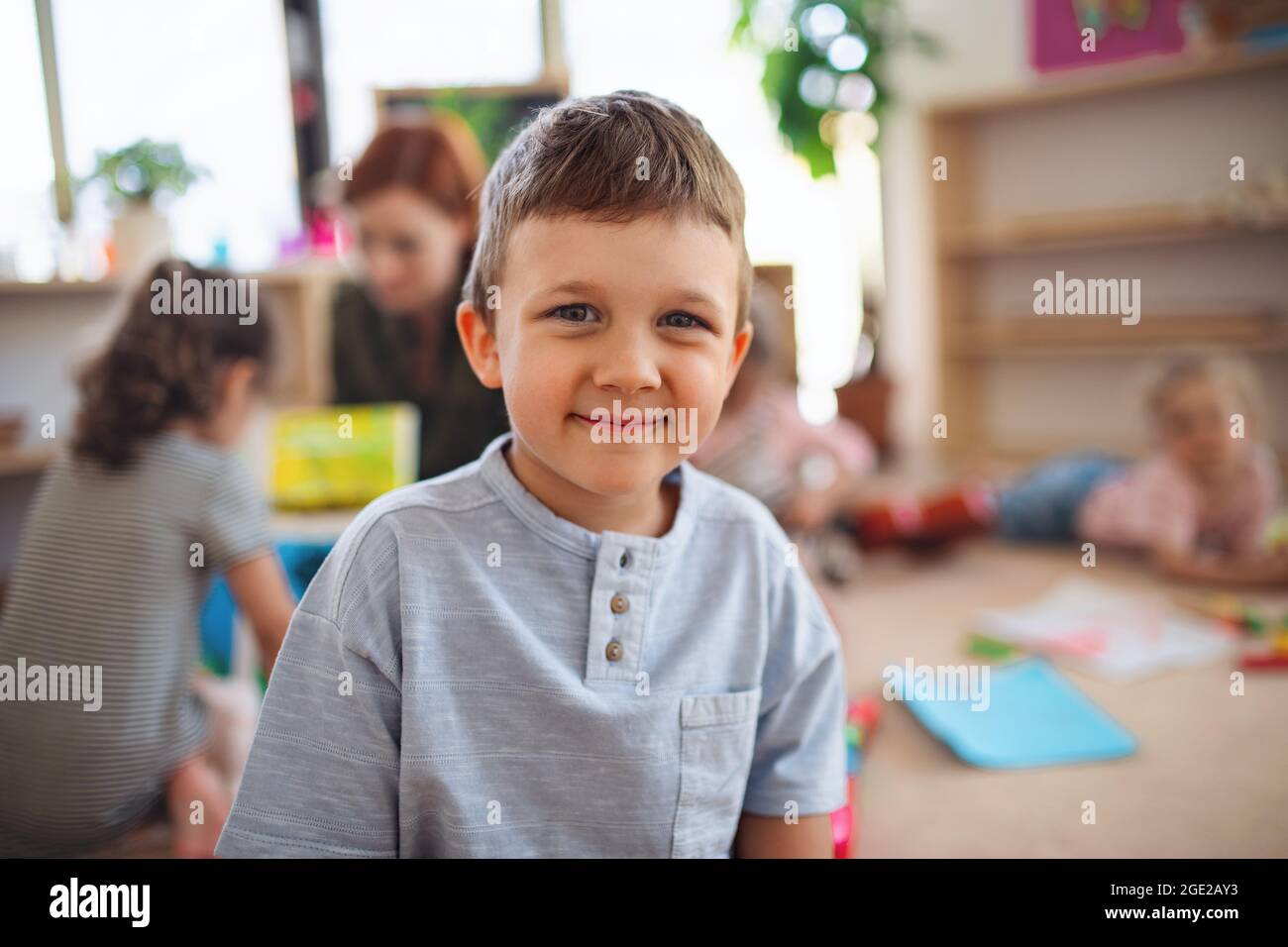 Ritratto di un piccolo ragazzo della scuola materna al coperto in classe, guardando la macchina fotografica. Foto Stock