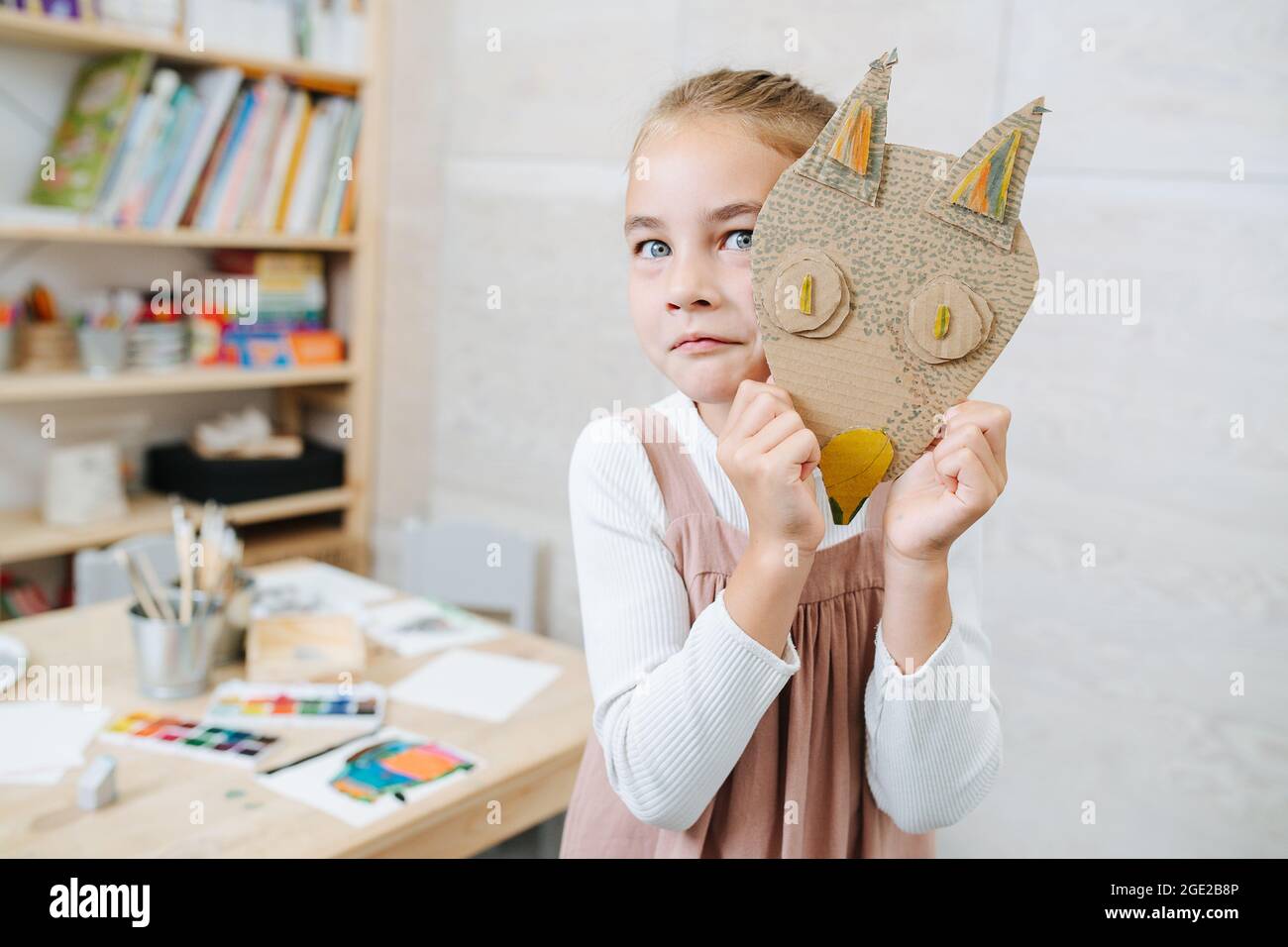 Grimacing bambina picchiata da un lato di cartone volpe maschera fatta a mano Foto Stock