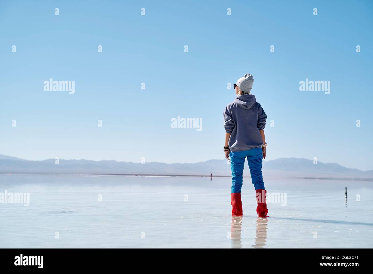 donna asiatica in piedi nell'acqua di un lago di sale che guarda alla vista Foto Stock