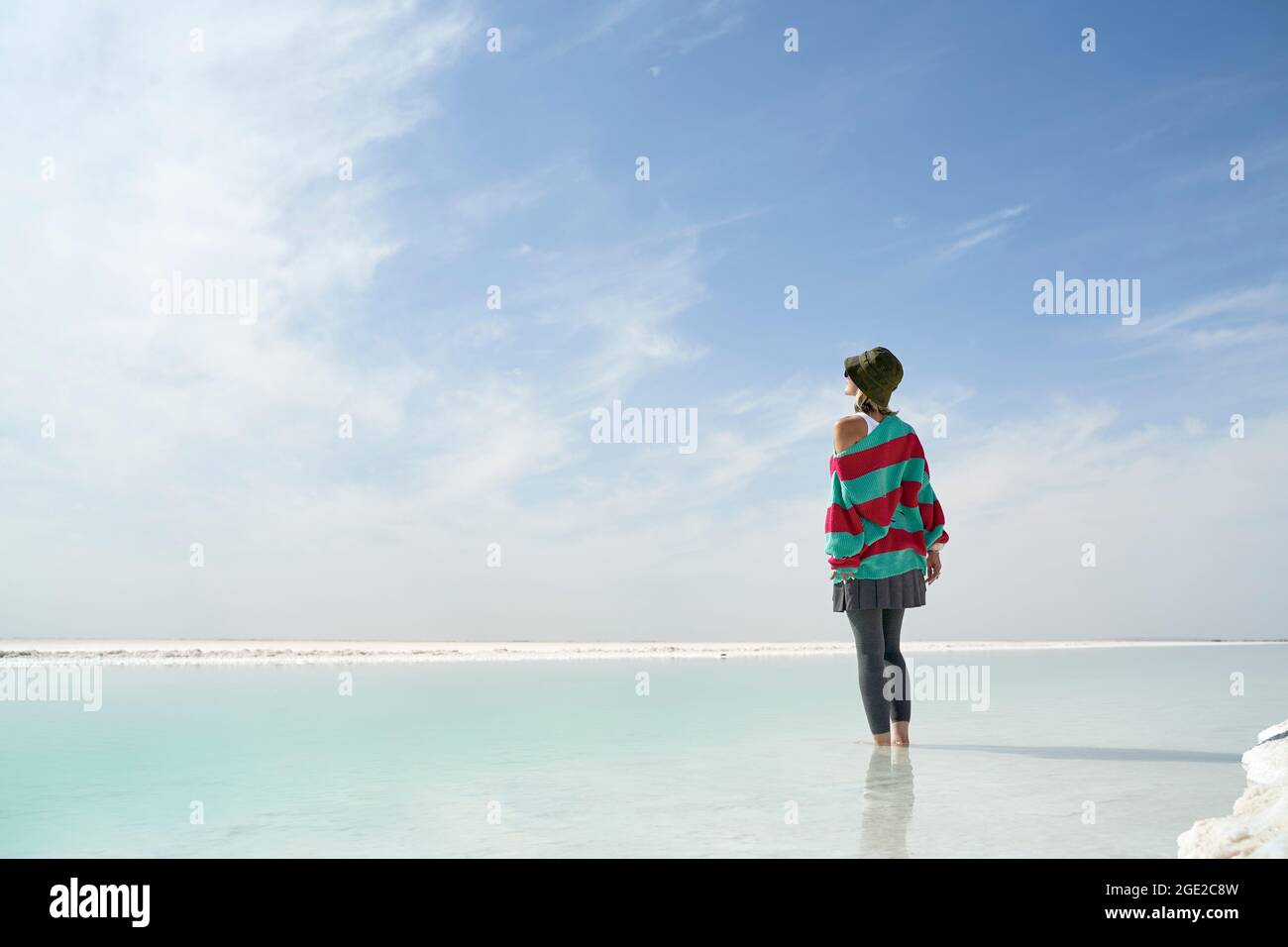 donna asiatica in piedi nell'acqua di un lago di sale che guarda alla vista Foto Stock