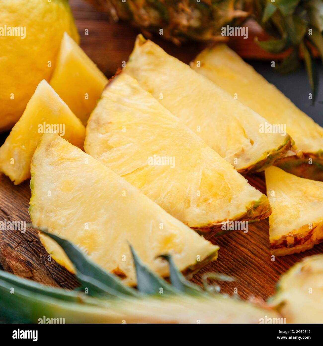Ananas a fette sul tagliere. Frutta estiva affettare ananas a fette processo in cucina su sfondo scuro. Quadrato Foto Stock