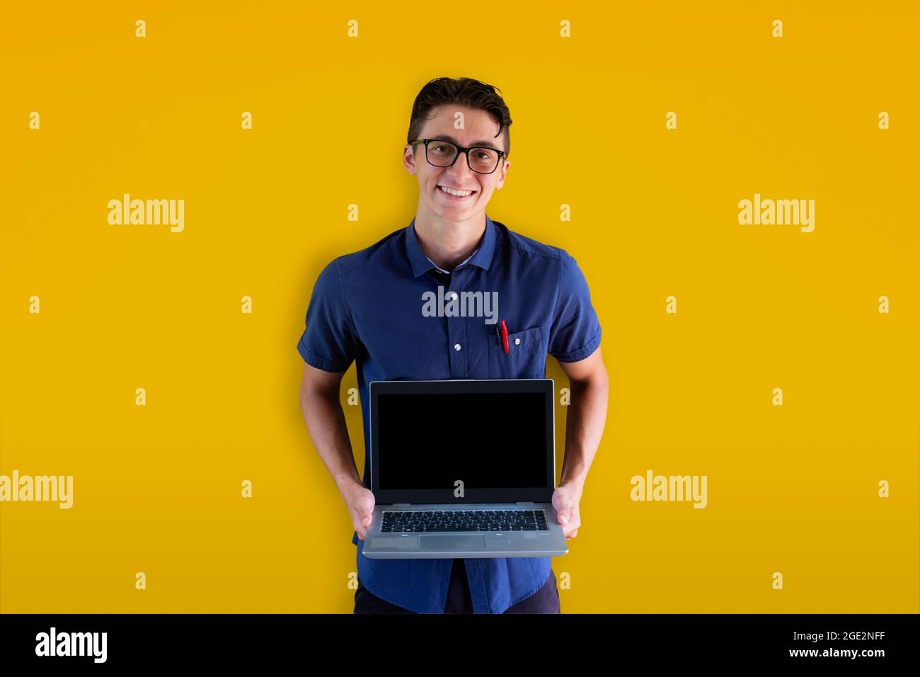 Giovane ragazzo caucasico che tiene un laptop su sfondo giallo. Modello perfetto per cyber Monday, messaggi promozionali e pubblicità. Faccia sorridente. Foto Stock