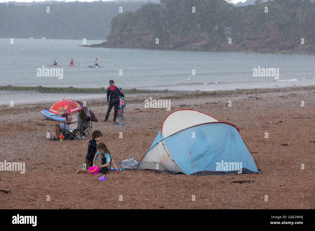I vacanzieri hanno coraggioso gli elementi di Goodrington North Beach a Paignton, Devon, colpiti da docce tuose che costringono alcuni turisti a correre per coprire, Regno Unito. Foto Stock