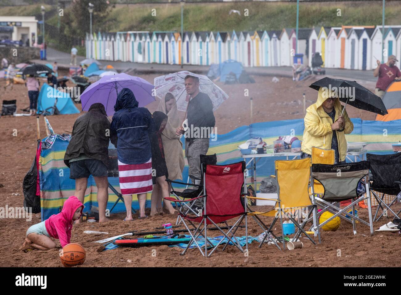 I vacanzieri hanno coraggioso gli elementi di Goodrington North Beach a Paignton, Devon, colpiti da docce tuose che costringono alcuni turisti a correre per coprire, Regno Unito. Foto Stock