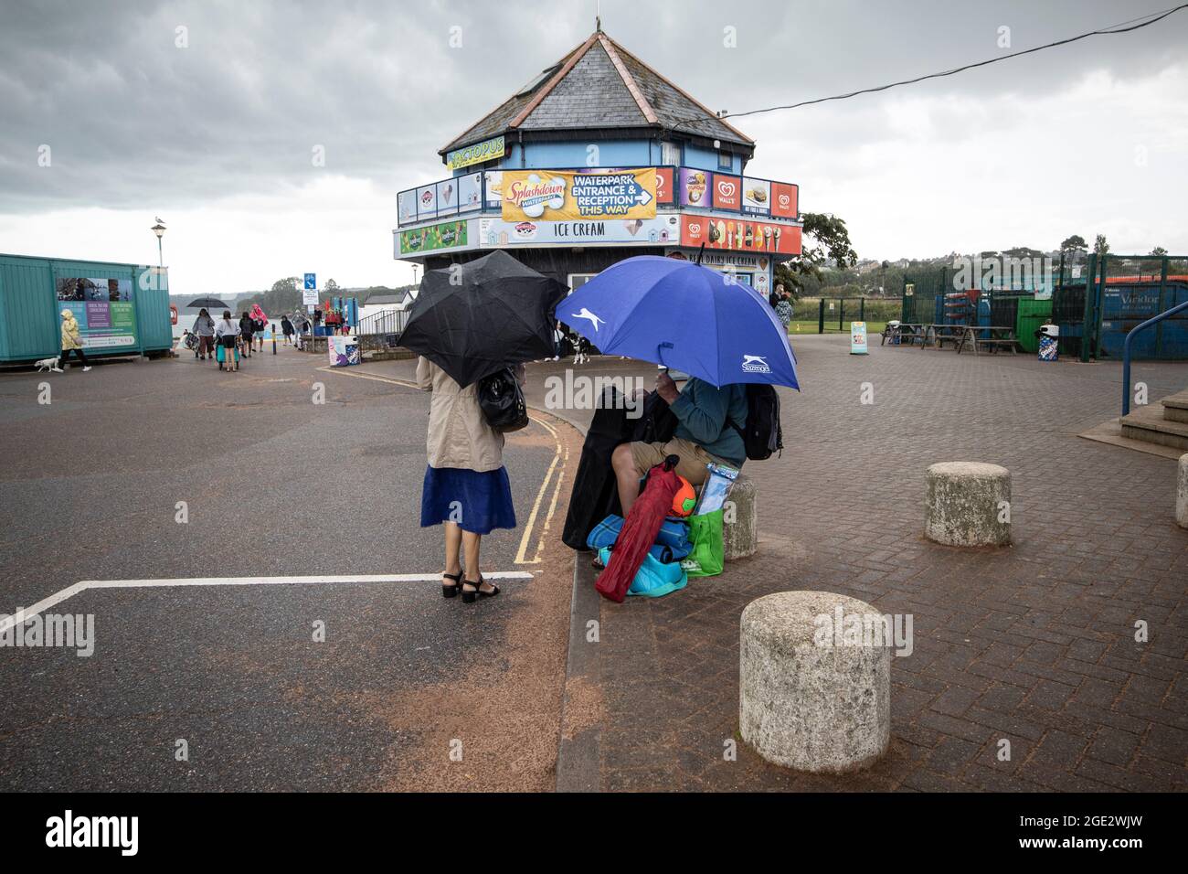 I vacanzieri hanno coraggioso gli elementi di Goodrington North Beach a Paignton, Devon, colpiti da docce tuose che costringono alcuni turisti a correre per coprire, Regno Unito. Foto Stock