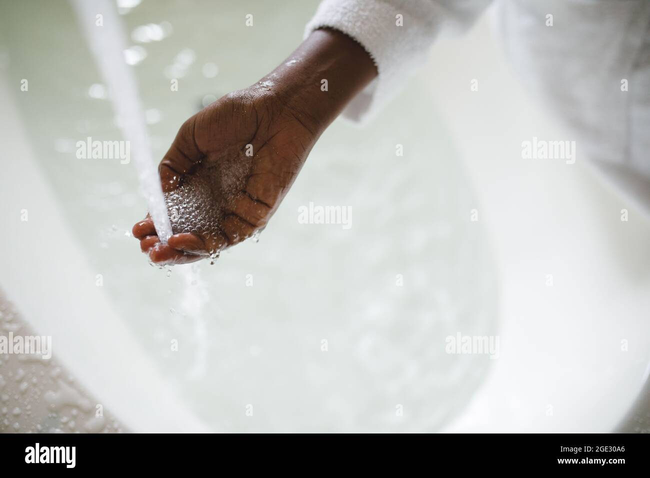 Primo piano di mano di donna afroamericana in bagno che fa funzionare un bagno Foto Stock