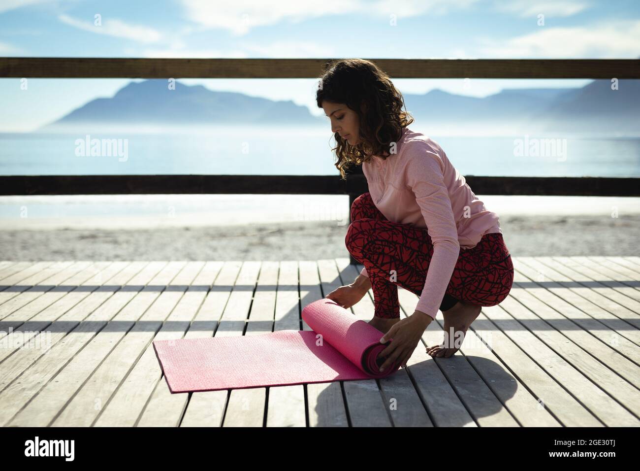 Donna da corsa mista che pratica yoga in giornata di sole al mare Foto Stock