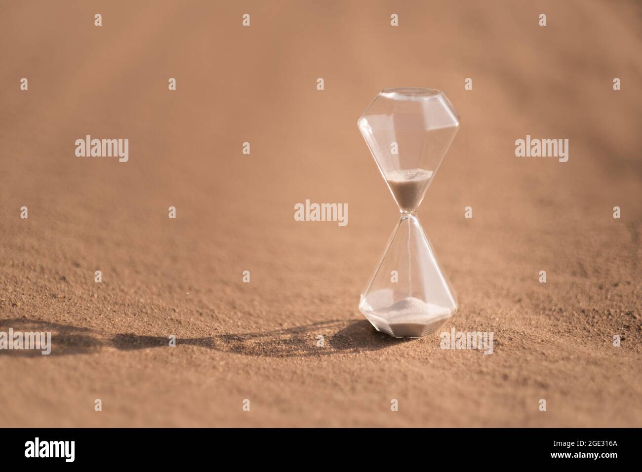 Una clessidra sulla sabbia calda nel deserto al caldo sole estivo. Foto Stock