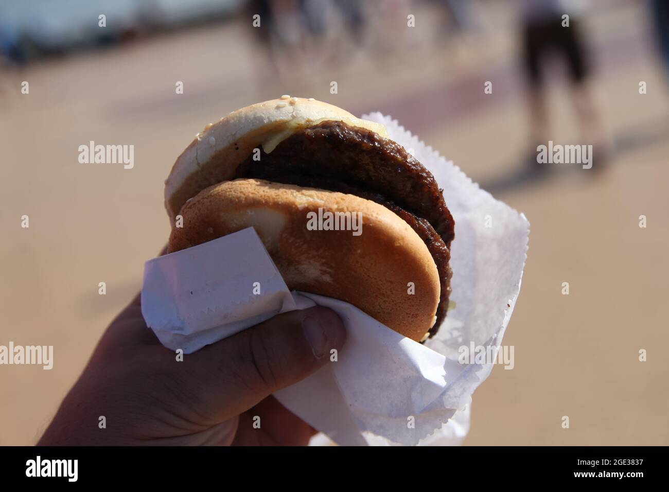Cheeseburger doppio in mano, hamburger fast food, lungomare Barry Island, Galles del Sud, 2021 Foto Stock