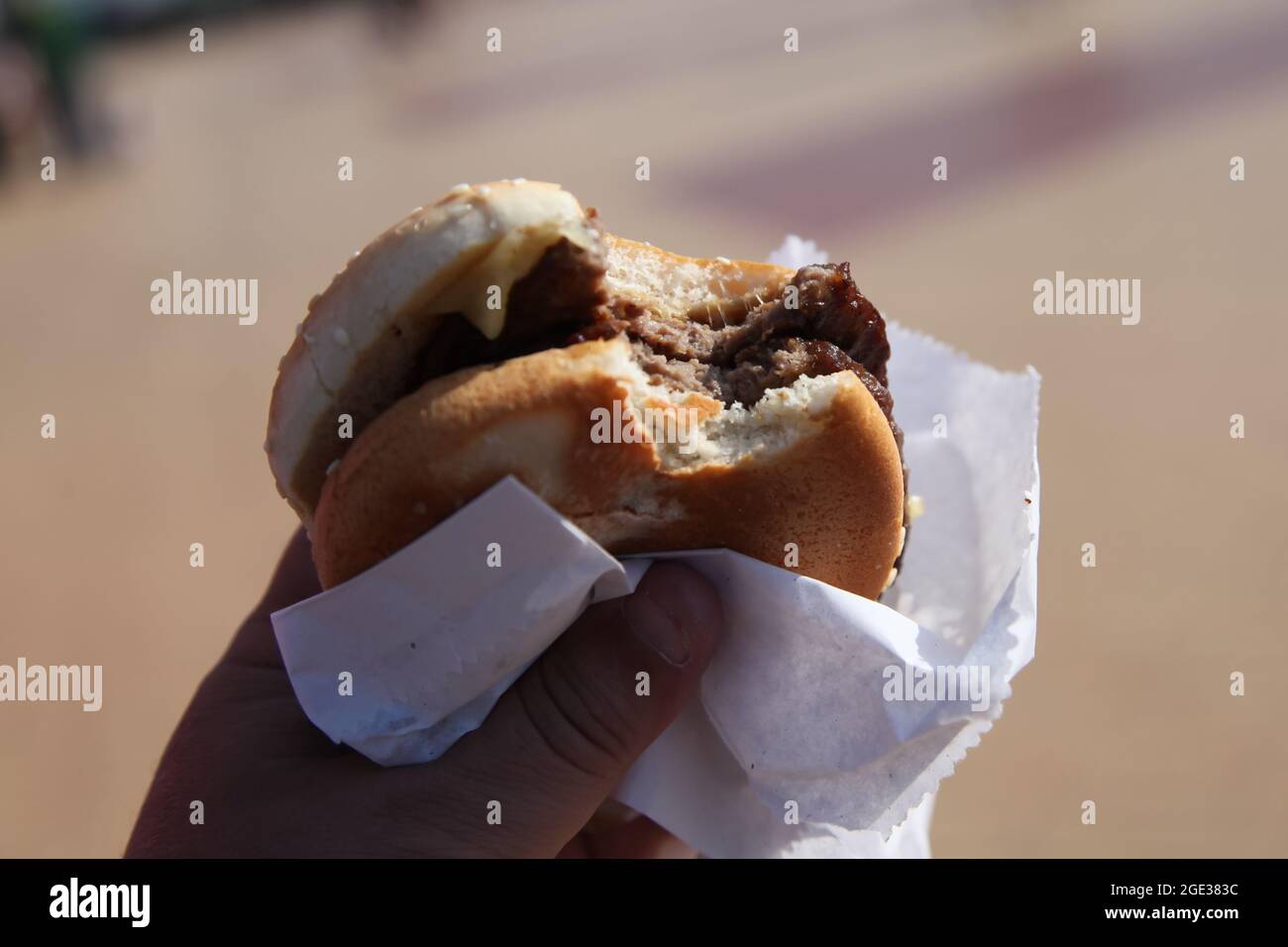 Doppio cheeseburger in mano con spuntini, hamburger fast food, lungomare Barry Island, Galles del Sud, 2021 Foto Stock