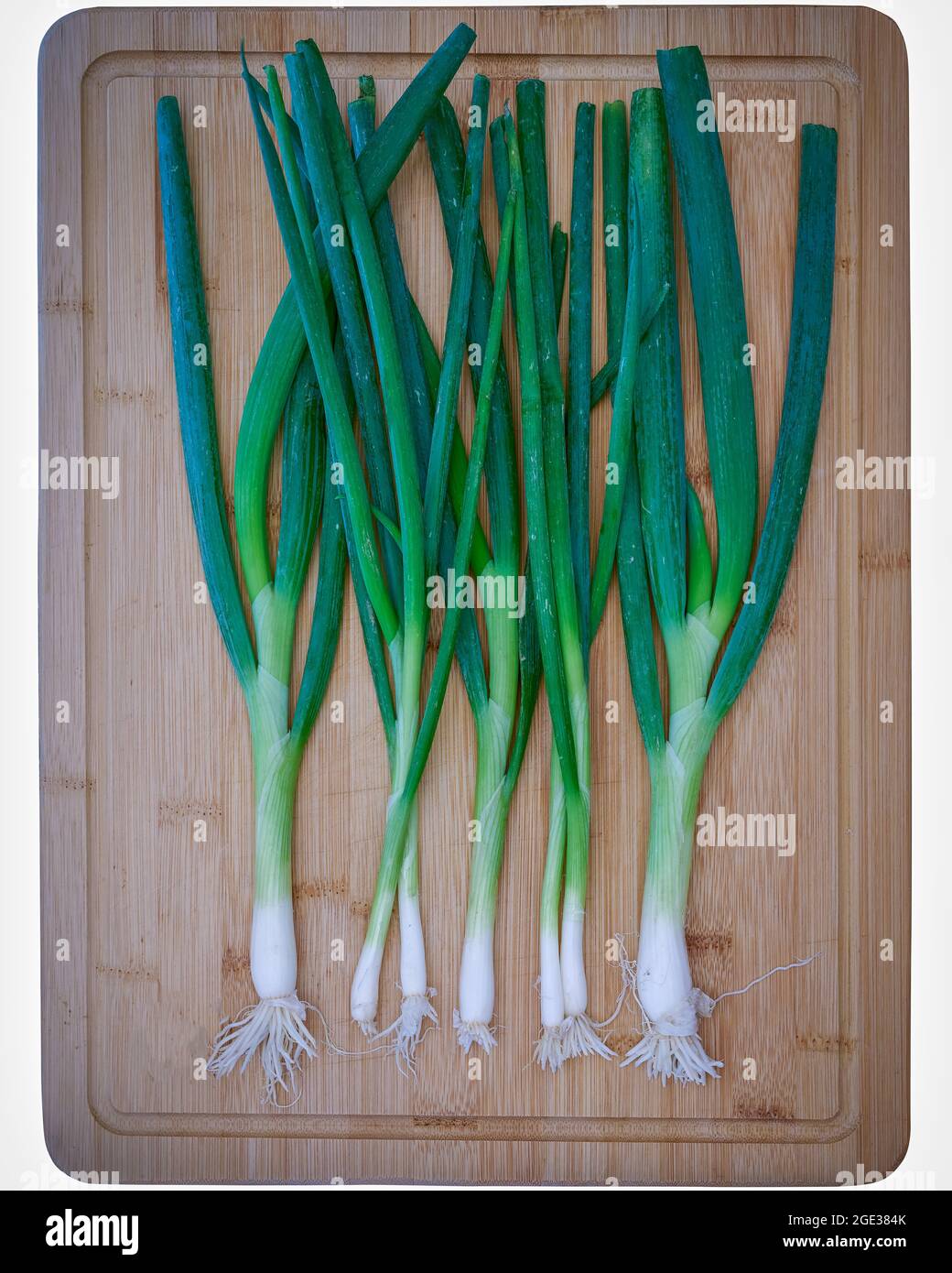 Food, Deutschland, Frühlingszwiebeln liegen auf einem Schneidebrett aus Bambus Foto Stock