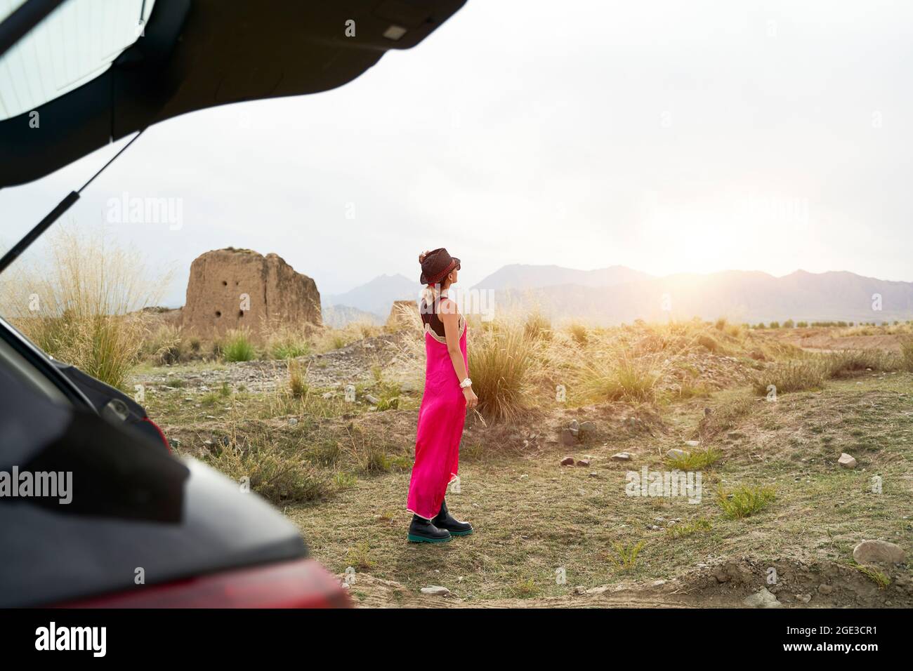 giovane donna asiatica viaggiatore in auto vestito rosso godendo la luce del sole del mattino sulla strada Foto Stock