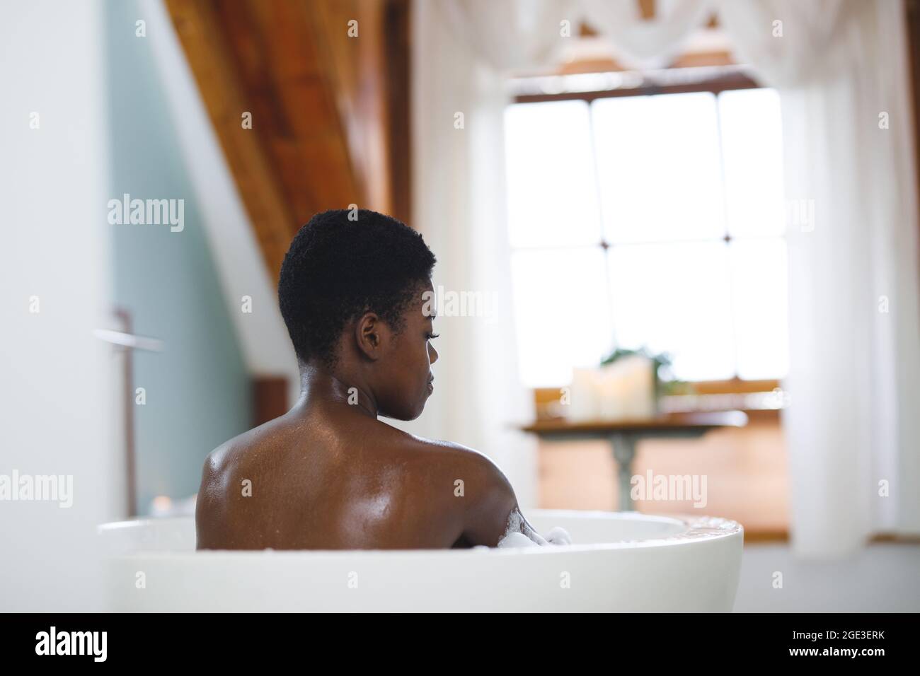 Donna afroamericana sorridente in bagno, rilassante in bagno Foto Stock