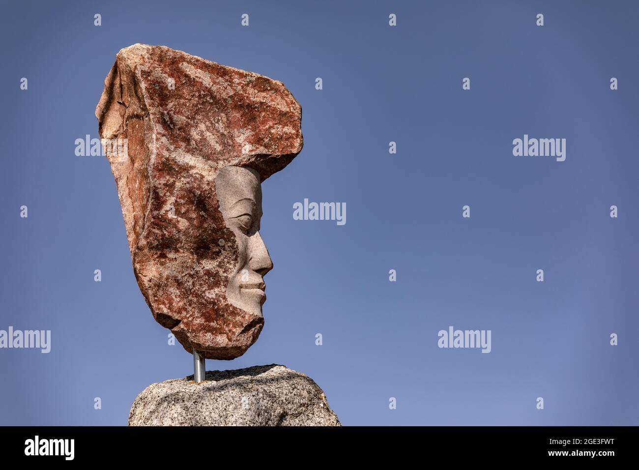 Impressionante statua di pietra di granito contro un cielo blu alla luce del sole Foto Stock