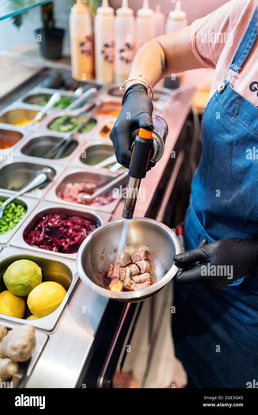 Operaio del ristorante non riconosciuto che indossa il grembiule che  prepara la ciotola del poke e che usa il cannello della cucina Foto stock -  Alamy