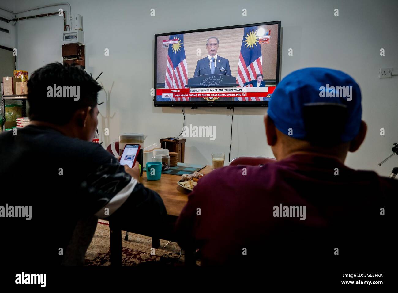 La gente guarda il discorso del primo ministro Muhyiddin Yassin su uno schermo televisivo a Kuala Lumpur.il primo ministro malese Muhyiddin Yassin ha annunciato le sue dimissioni durante una conferenza stampa ufficiale presso l'ufficio del primo ministro (PMO) a Putrajaya. Foto Stock