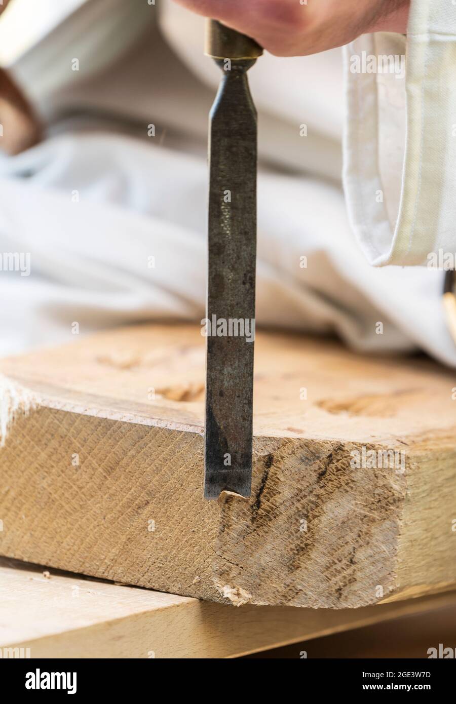 Primo piano di una lama di scalpello mentre taglia un legno che si rade da un blocco di legno duro. Foto Stock