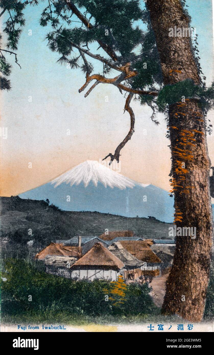 Vecchia cartolina giapponese colorata a mano, circa 1900, del Monte Fuji con il villaggio di Iwabuchi in primo piano incorniciato sul lato da un albero. Foto Stock
