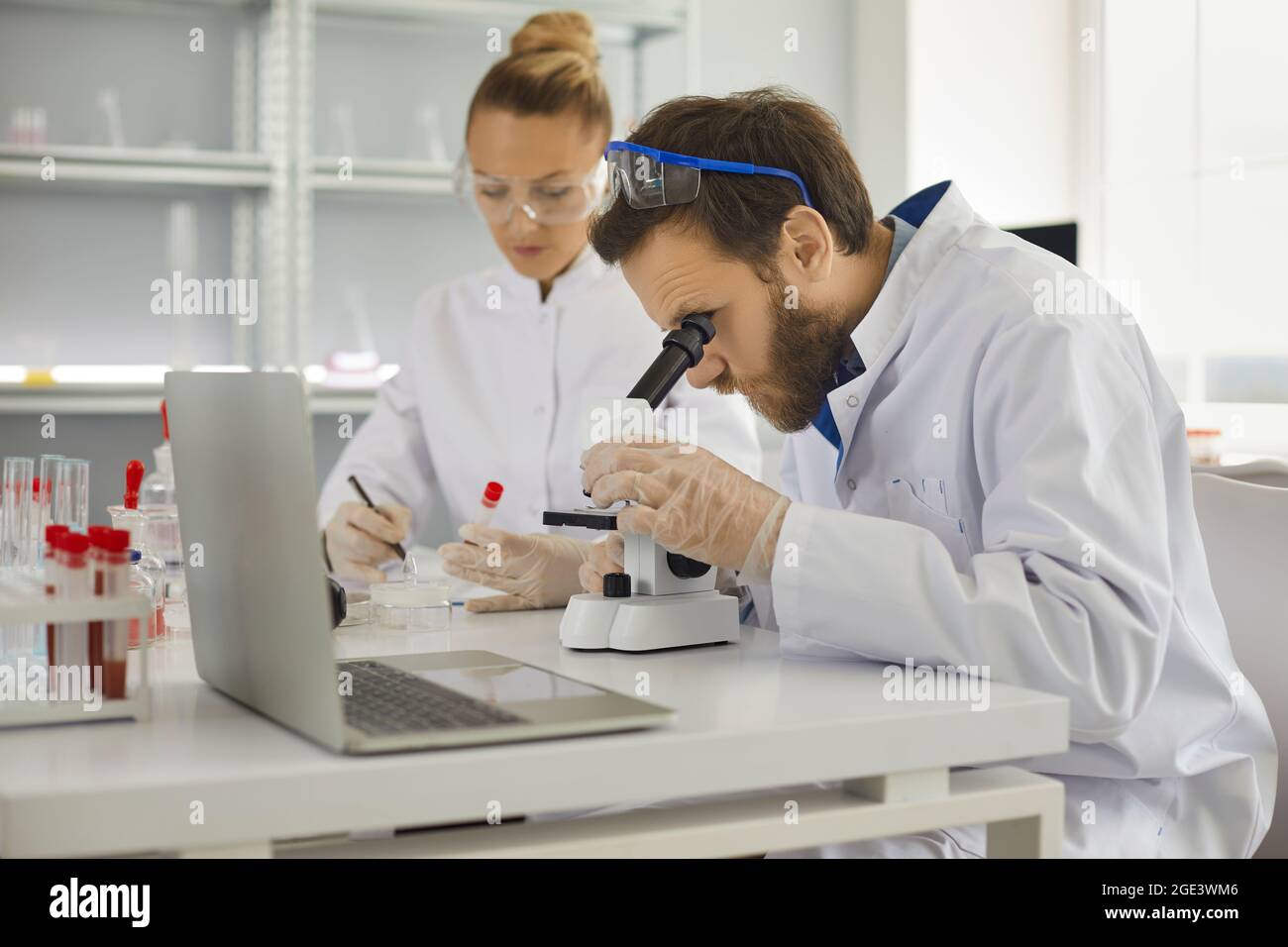 Ricercatori esperti di laboratorio che lavorano con campioni di analisi del sangue e microscopio Foto Stock