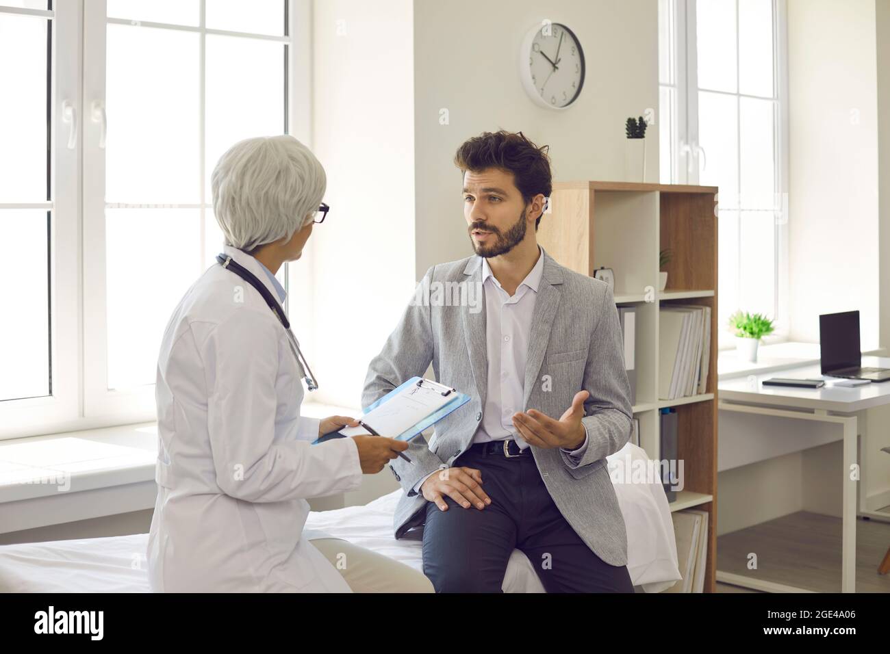 Giovane uomo che discute il suo trattamento con il medico in ufficio medico o sala esame Foto Stock