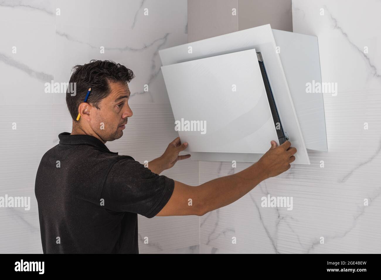 Uomo che monta un ventilatore in cucina Foto Stock