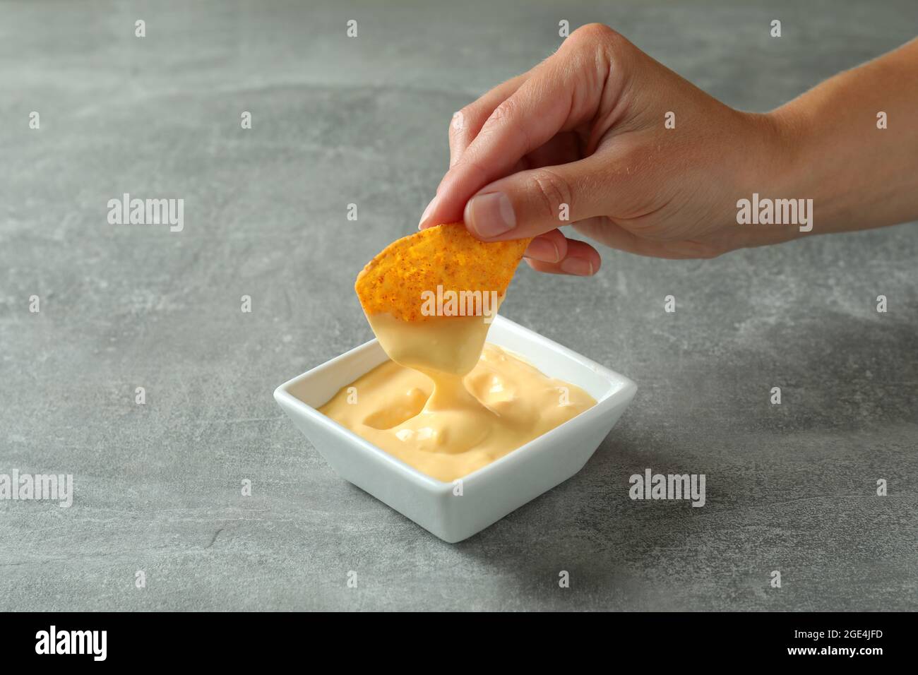 La mano femminile si immerge in salsa di formaggio, primo piano Foto Stock
